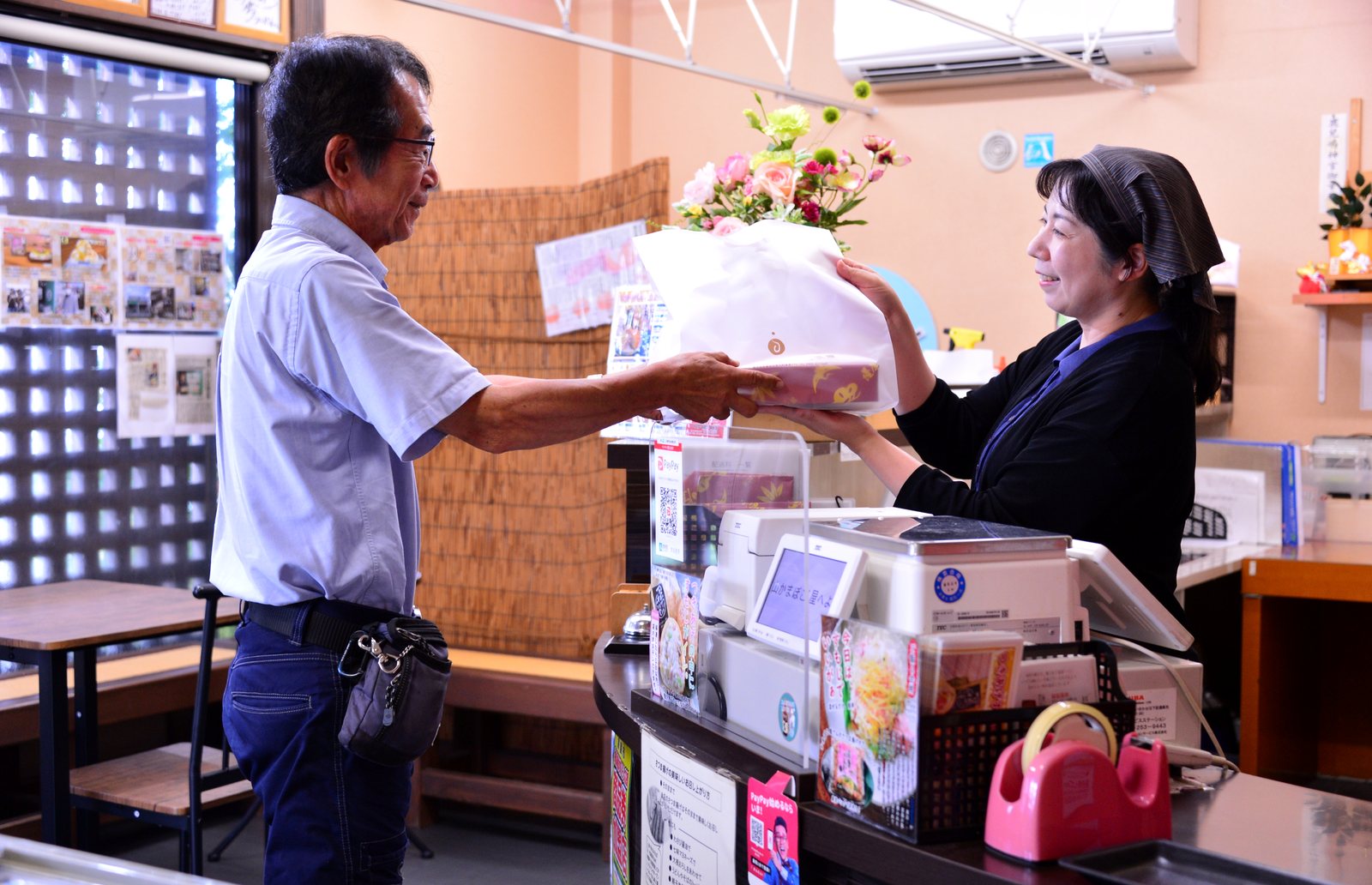 店内で贈答品を手渡す女将